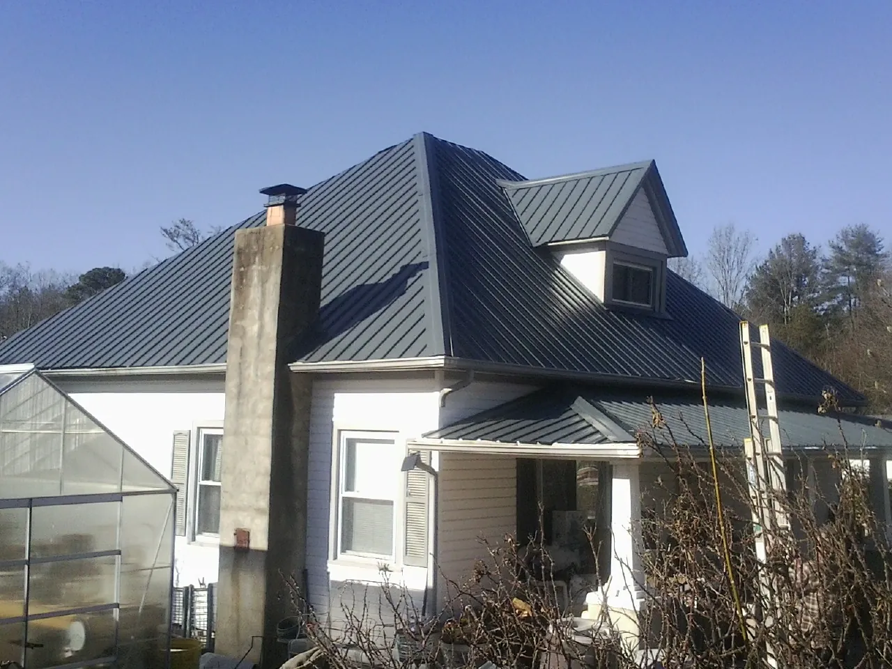 Dark blue standing seam metal roof on a white farmhouse with dormer — Slate & Tile Roof Repair by Roofing Brothers in Waccabuc