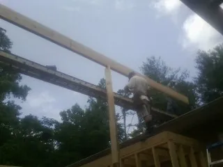 Carpenter setting a ridge beam over a new addition frame — Ice Dam Removal by Roofing Brothers in Waccabuc