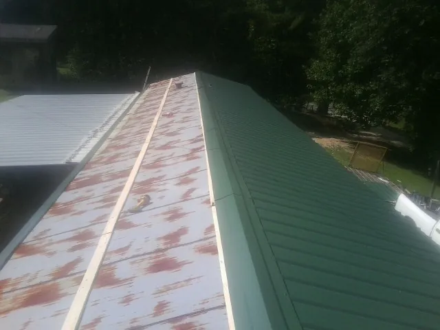 Old rusted panels beside newly installed green metal roofing — Wind Damage Roof Repair by Roofing Brothers in Waccabuc