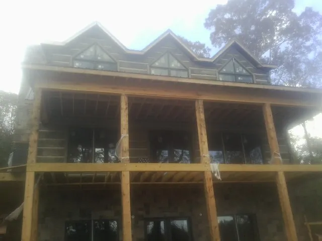Dormers and porch framing on a large log home under construction — Roof Coating work by our crew in Waccabuc