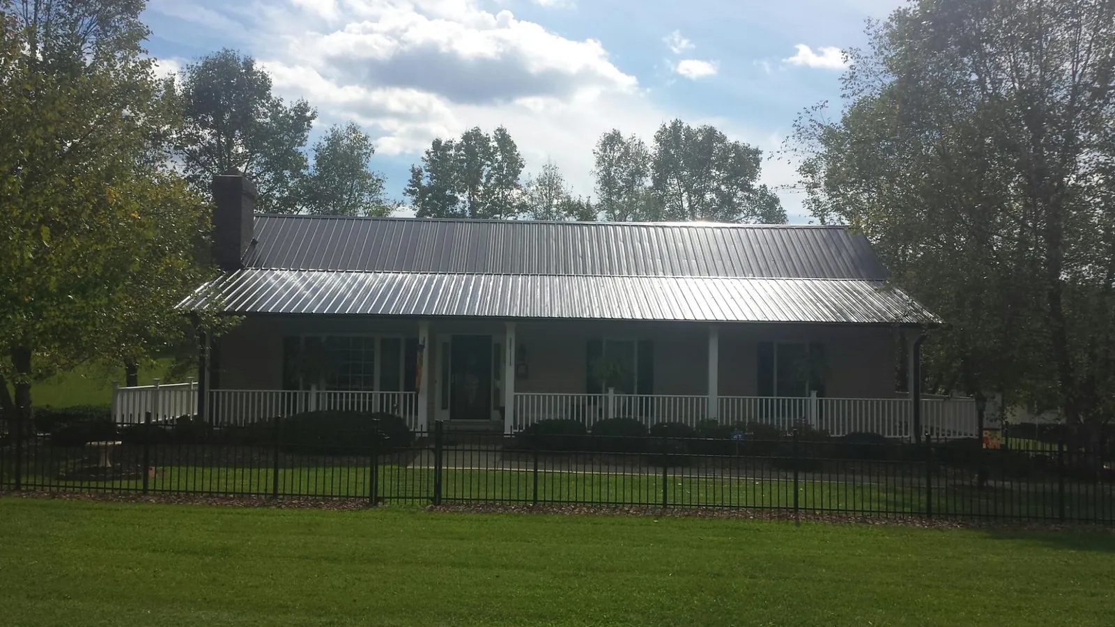 Gray metal roof on a brick ranch with a full width front porch — Gutter Guard Installation work by our crew in Waccabuc