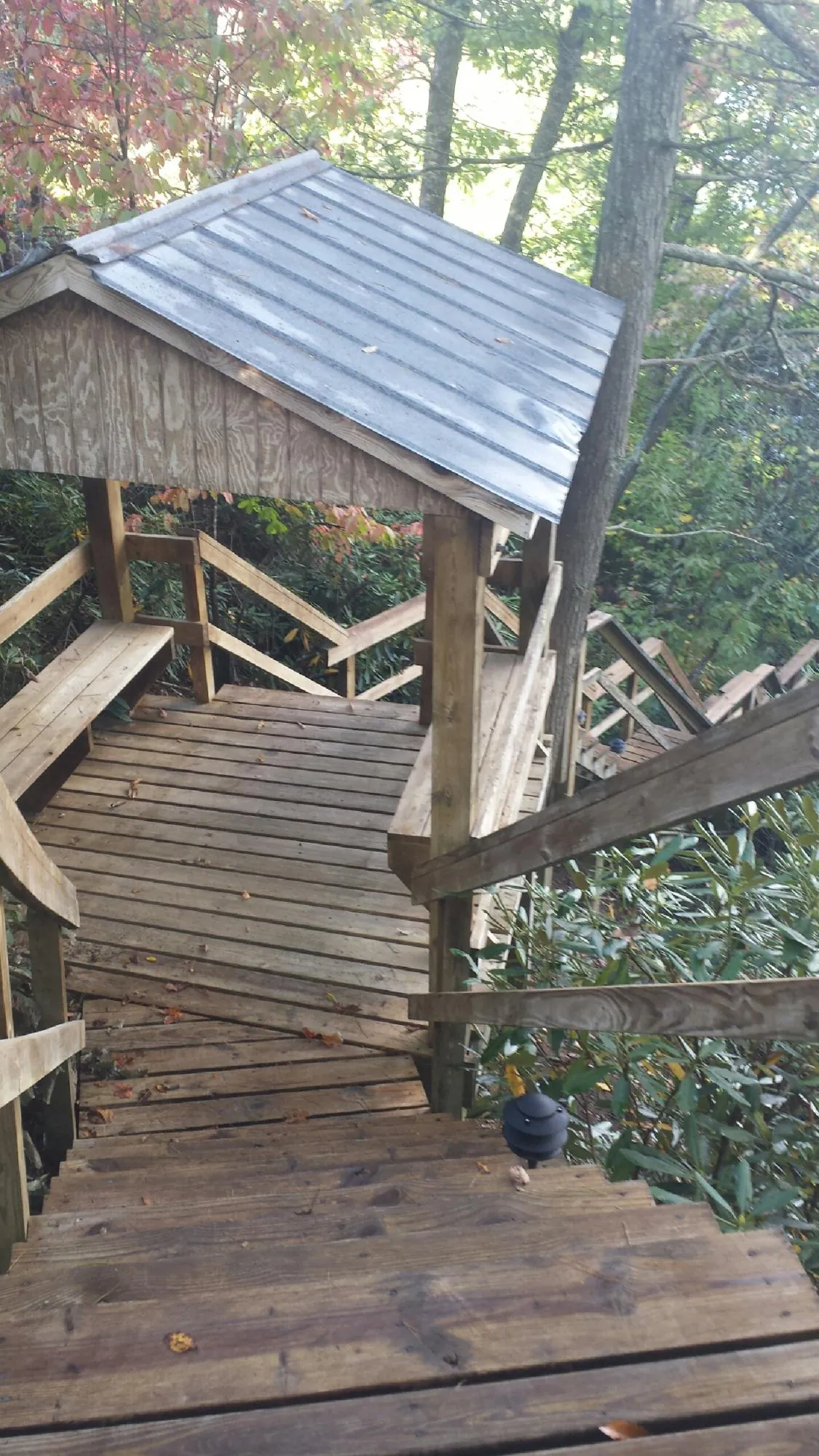 Metal roofed shelter over wooden steps on a wooded walkway — Skylight Repair & Installation work by our crew in Waccabuc