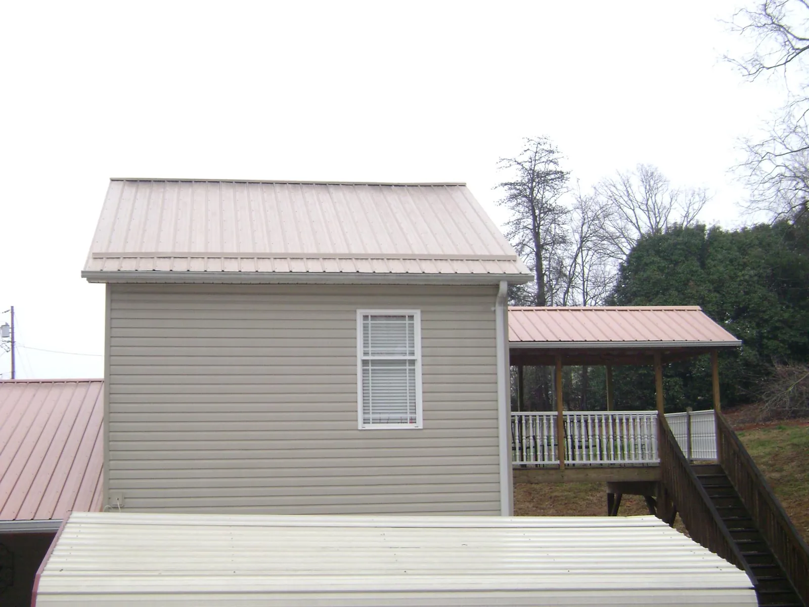 Tan metal roofs on a two story addition and attached porch, from a Roof Replacement job in Waccabuc