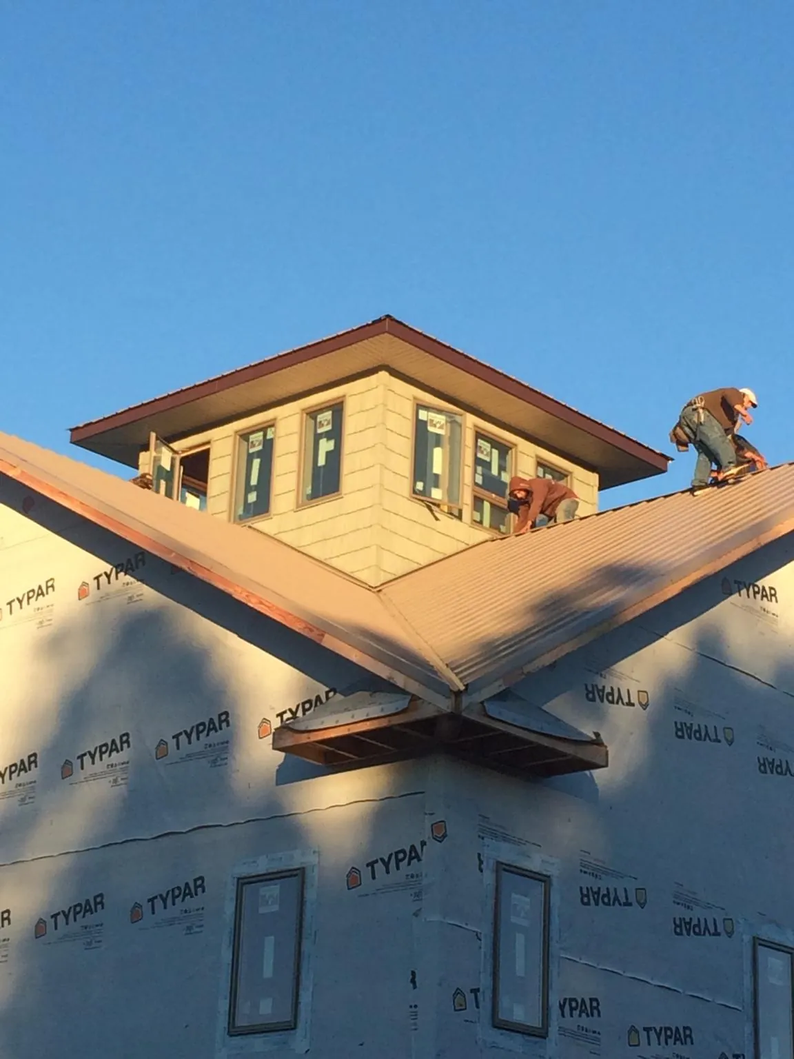 Roofers working around a rooftop cupola on a new metal roof at sunset — Roof Waterproofing in Waccabuc by Roofing Brothers